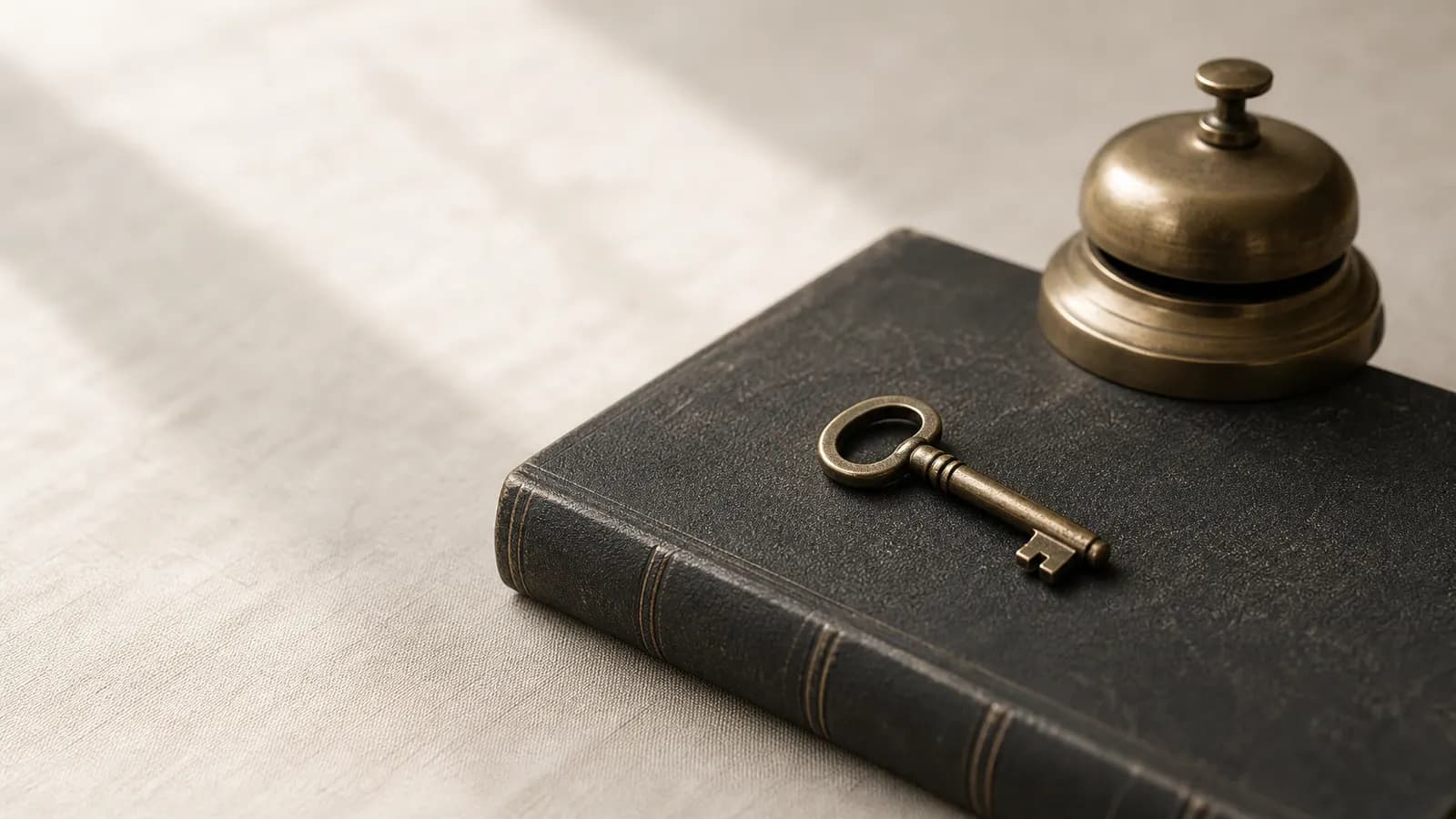 Brass key on a closed ledger beside a desk bell