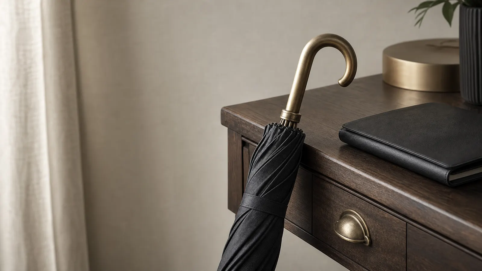 Charcoal umbrella with a brass handle leaning against a desk