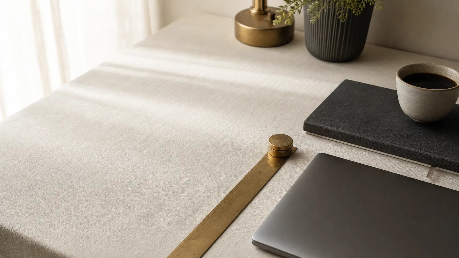 Desk with a brass ruler, notebook, laptop and coffee
