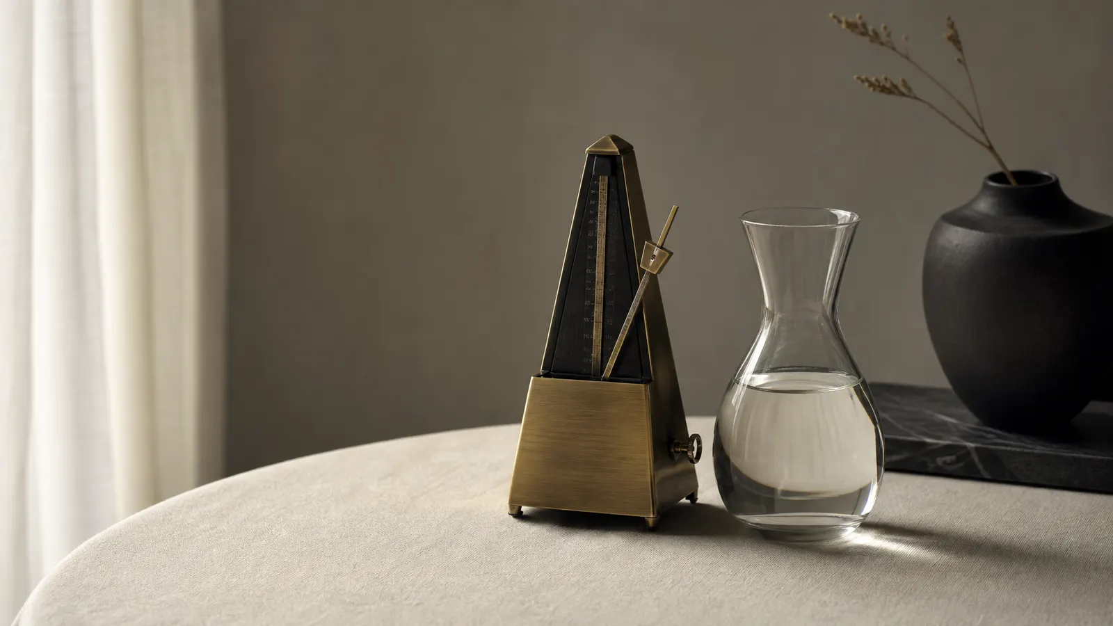 Brass metronome beside a glass carafe
