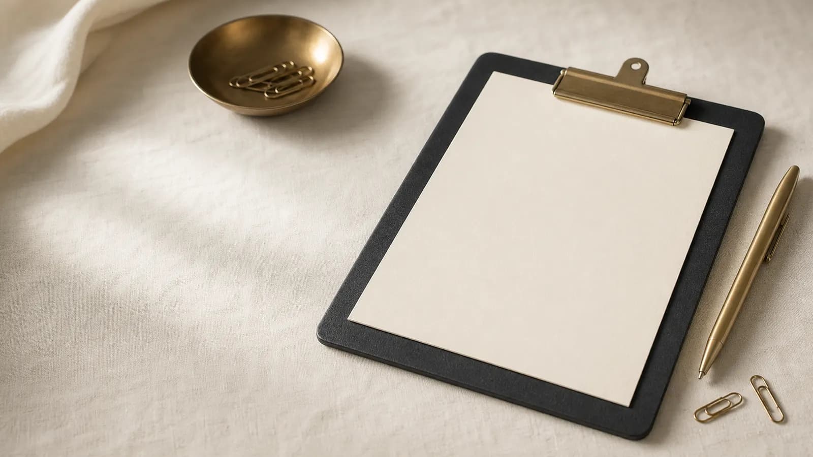 Clipboard with a blank sheet, a gold pen and paperclips