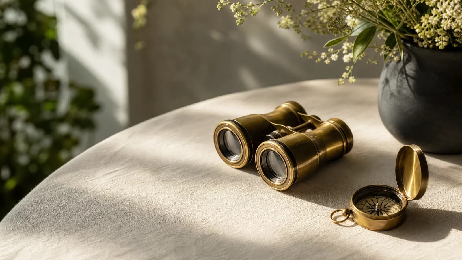 Brass binoculars and a compass on a garden table