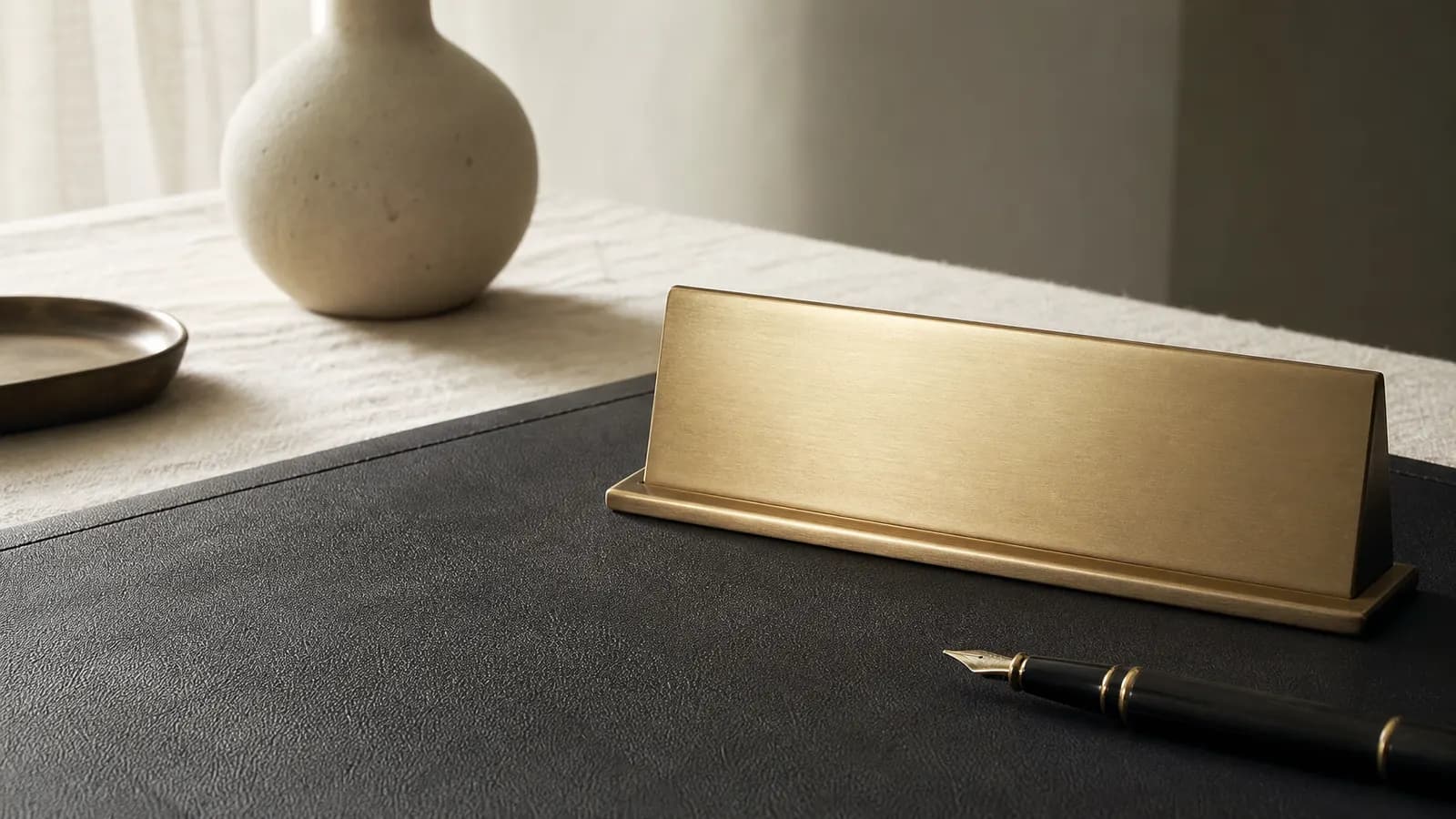 Blank brass nameplate and fountain pen on a desk