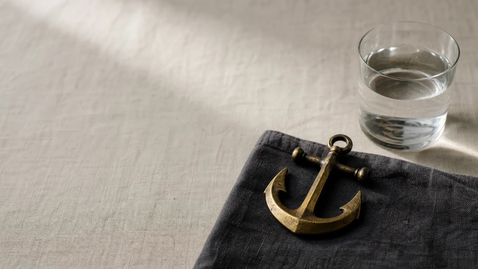 Brass anchor beside a still glass of water
